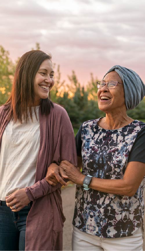 Photo of adult dauhter walking with her senior mother for an evening stroll.
